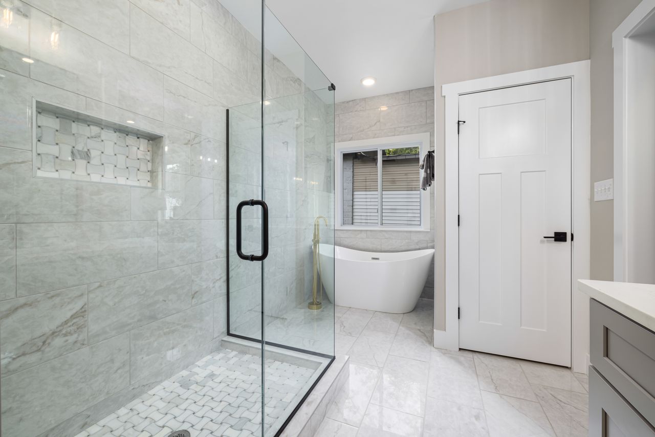trusted-partner Bright modern bathroom featuring a glass shower and freestanding bathtub. Perfect for design inspiration.
